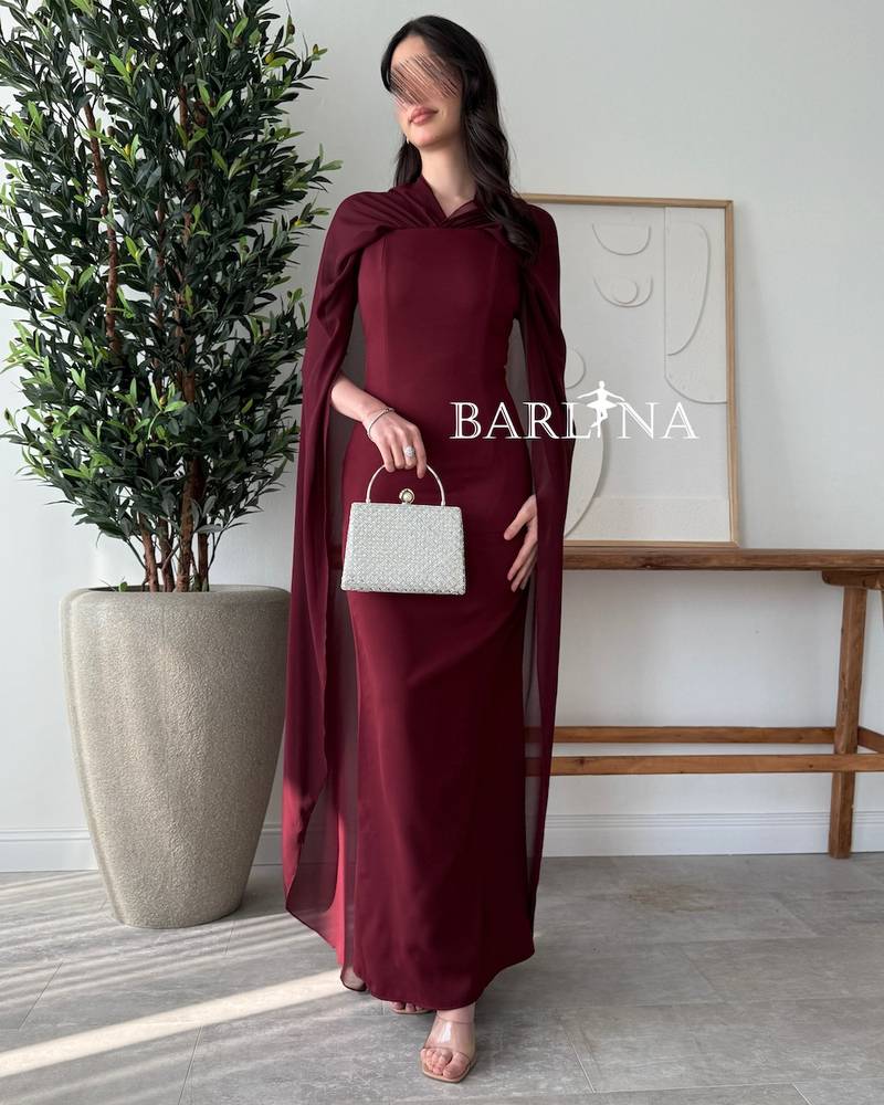 Burgundy dress with a cape draping from the shoulders