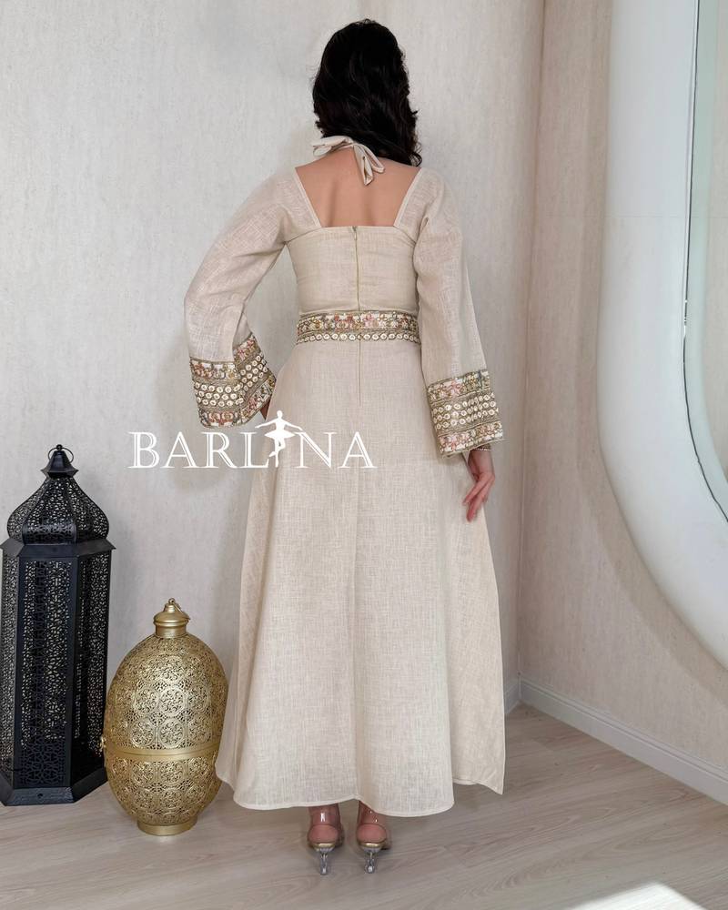 A soft beige jalabiya decorated with gold embroidery