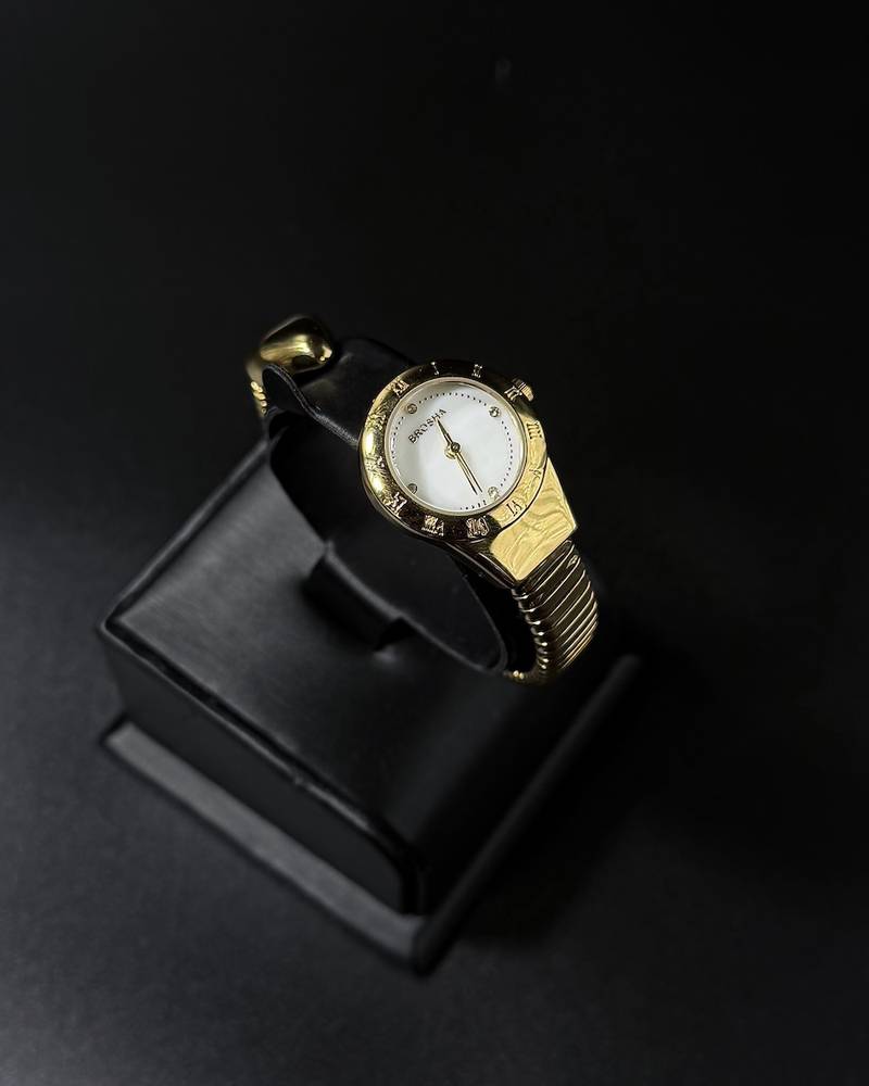 A women's watch with a delicate design and an open strap.