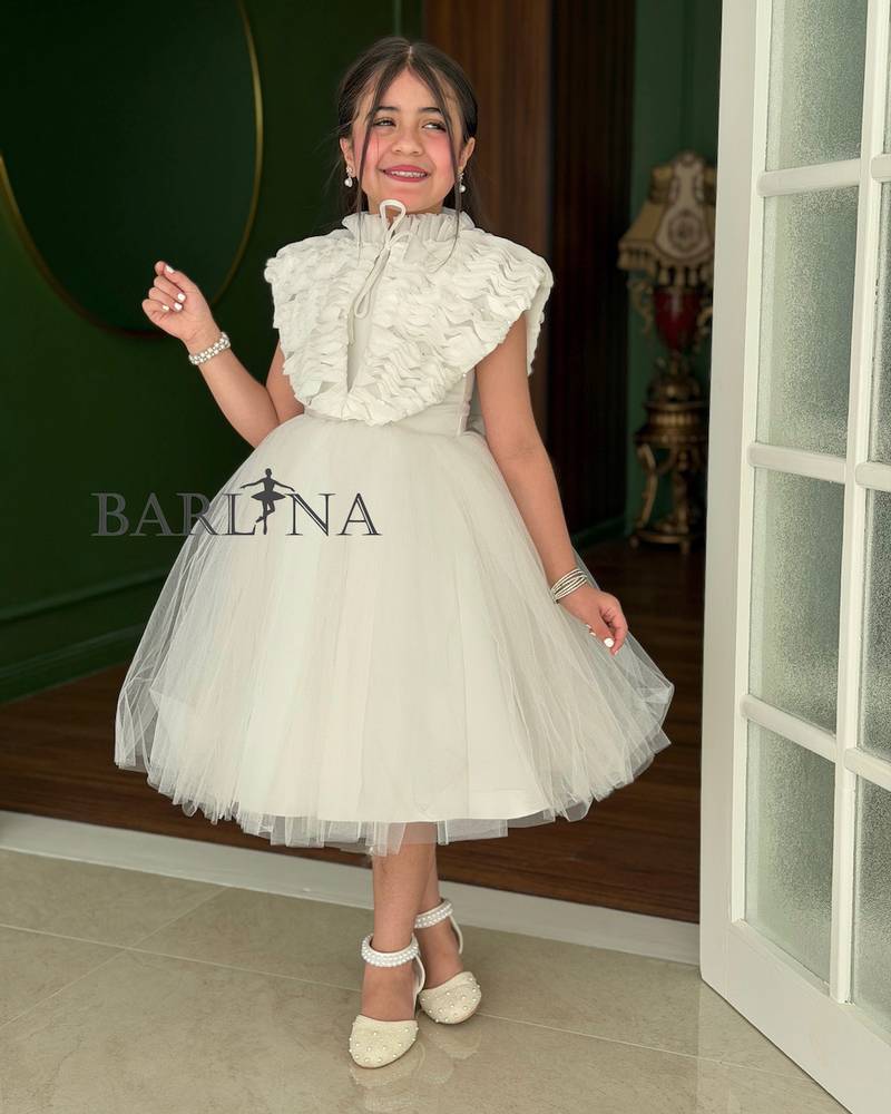 White girl's dress with a large ruffled shoulder