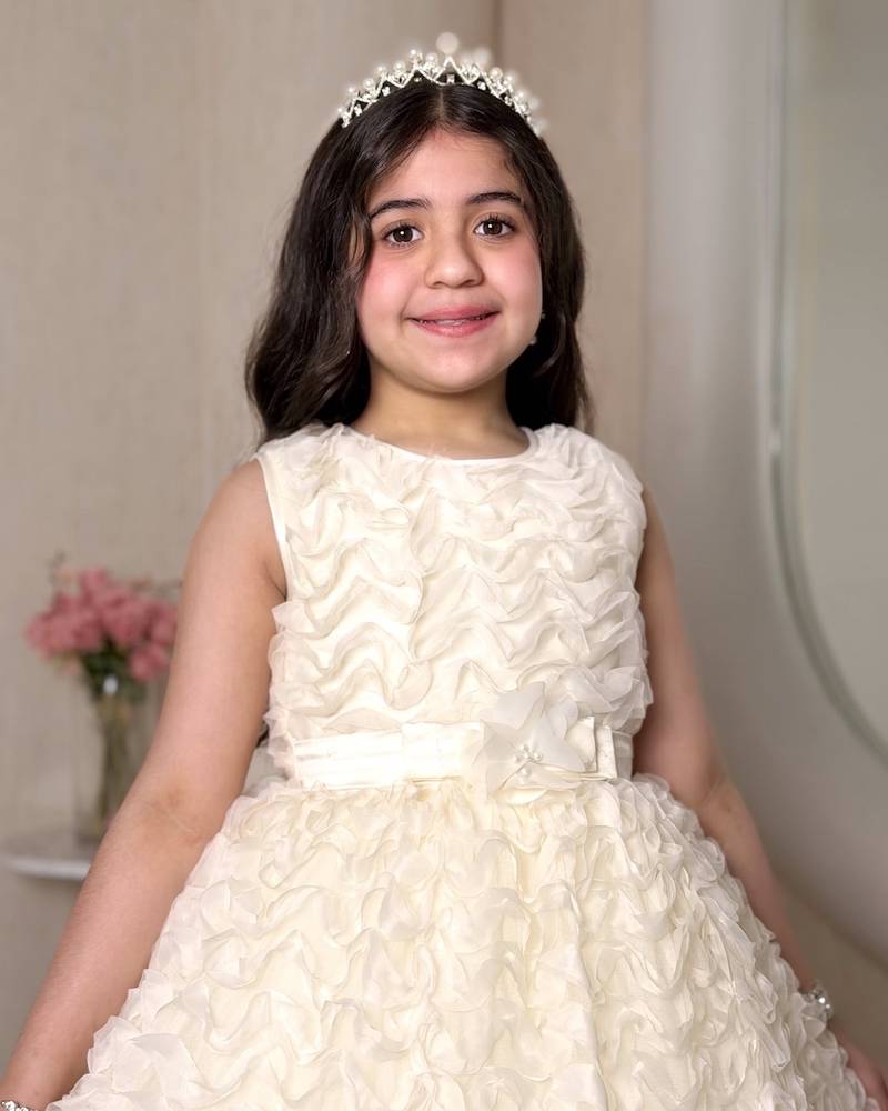 A cream-colored girl's dress adorned with elegant details
