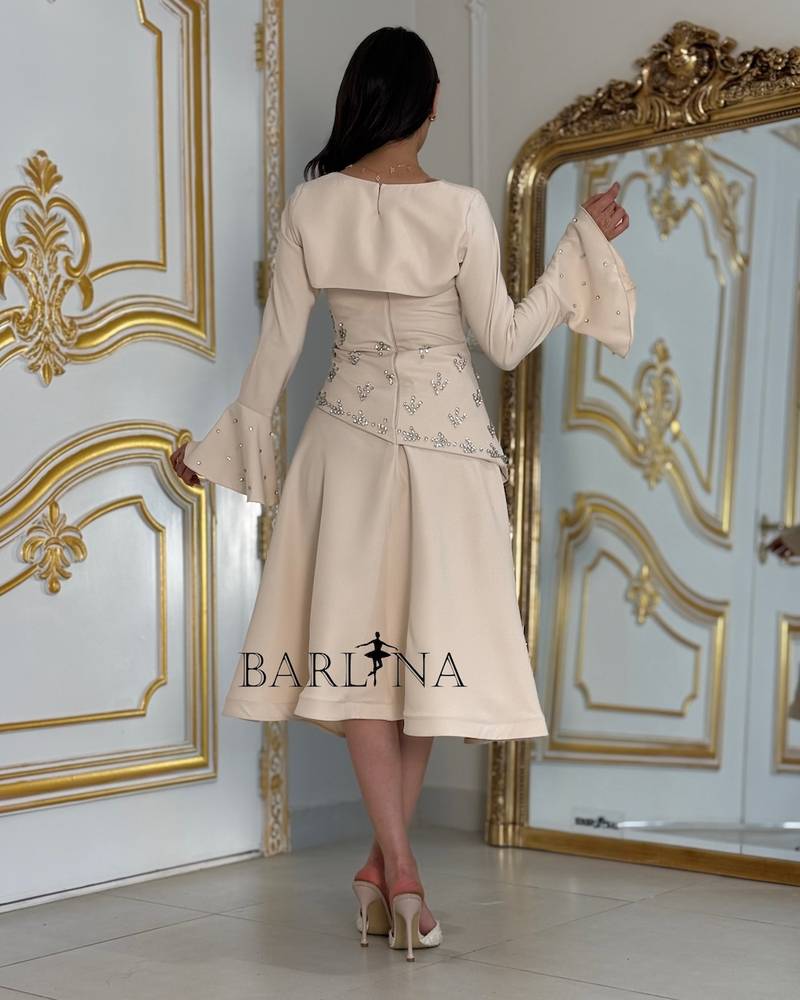 Beige dress adorned with crystals and a piece on the sleeve