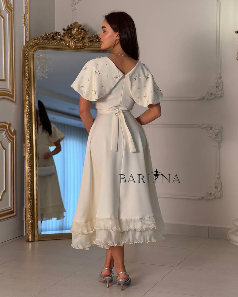 Dress with embroidered cape and pleats at the bottom