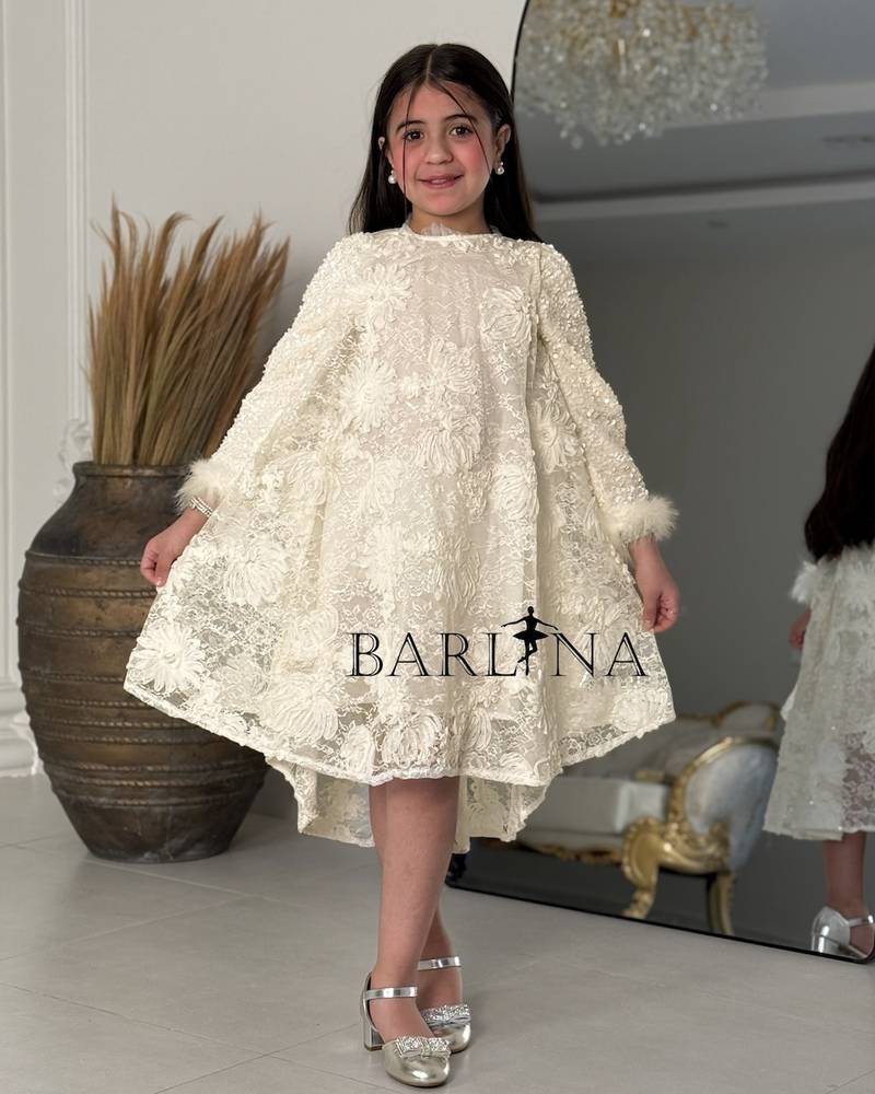 A cream-colored girl's dress with shimmering decorative details.