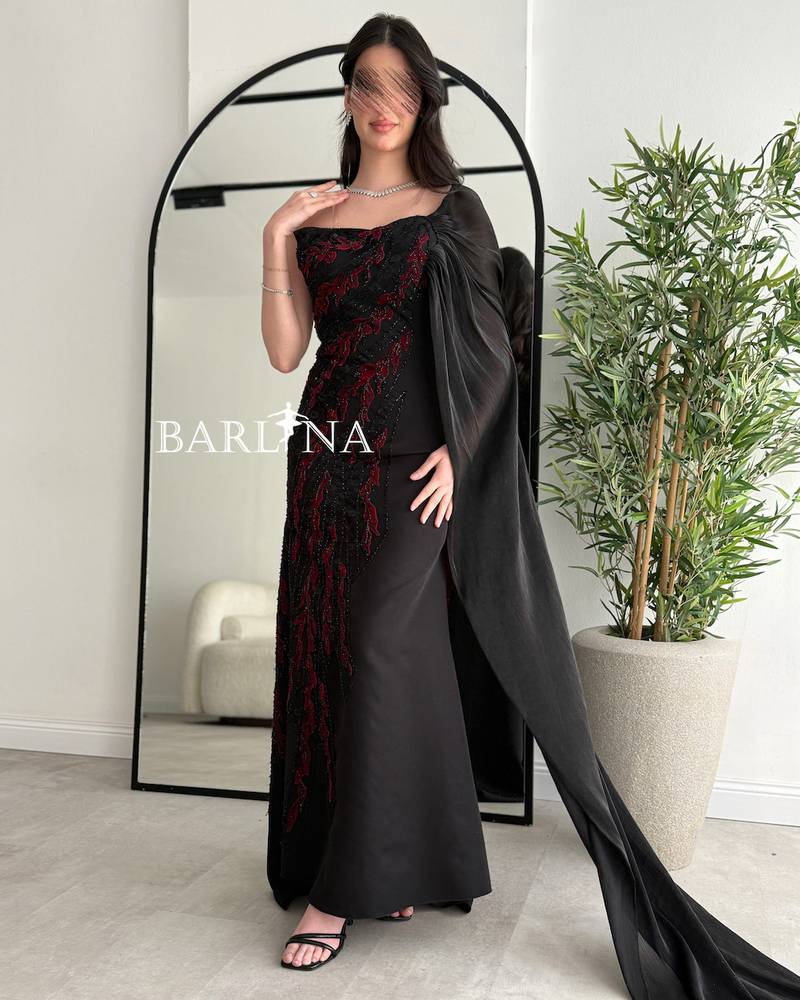 Black dress embroidered with red and with a side cape