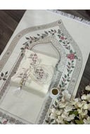 سجادة صلاة (أو شرشف صلاة) بلون سكري أو بيج مع نقوش زهرية وشرابة بيضاء.