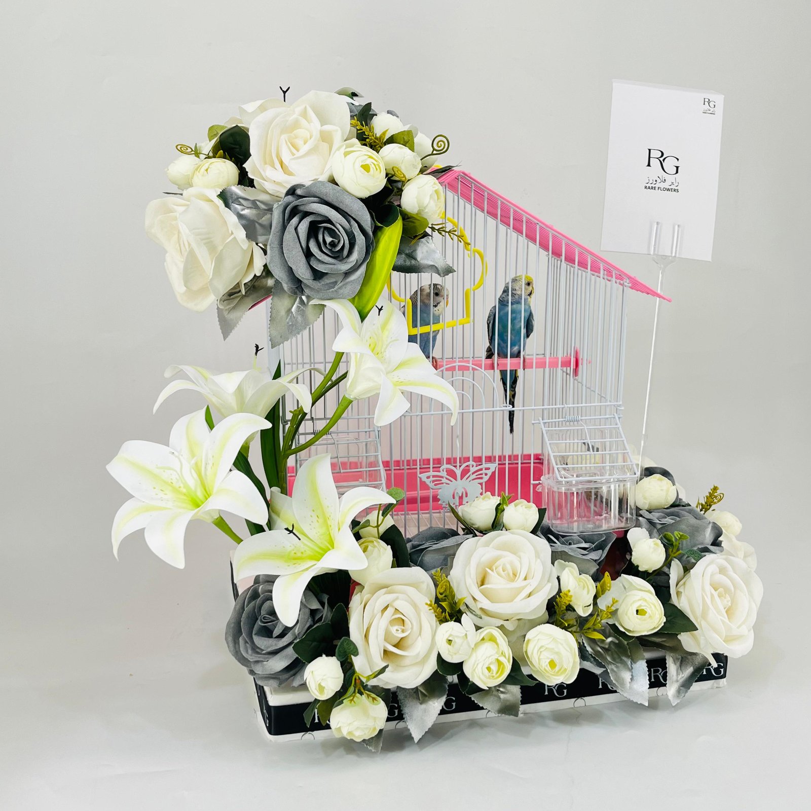 A pair of budgies with a cage decorated with colorful artificial flowers.03-177 - Image 2
