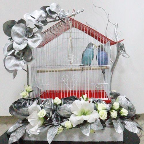 A pair of budgies with a cage decorated with colorful artificial flowers - Image 1