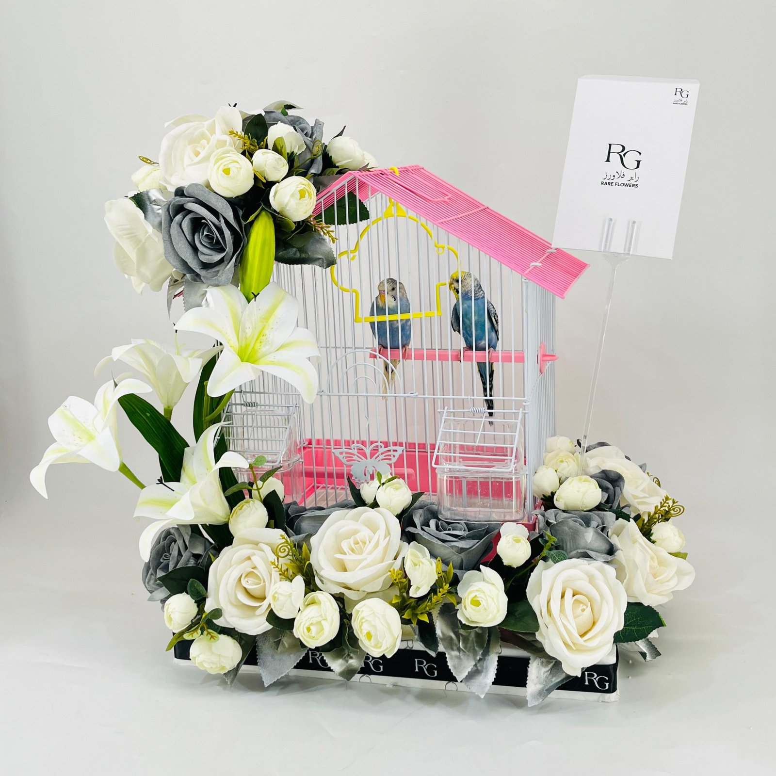 A pair of budgies with a cage decorated with colorful artificial flowers.03-177 - Image 3