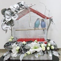 A pair of budgies with a cage decorated with colorful artificial flowers - Image 1