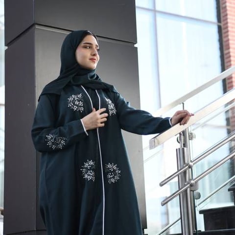 عباية لف باللون الأخضر الداكن مزينة بشك بارز وقيطان على اطراف العباية والاكمام