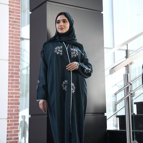 عباية لف باللون الأخضر الداكن مزينة بشك بارز وقيطان على اطراف العباية والاكمام