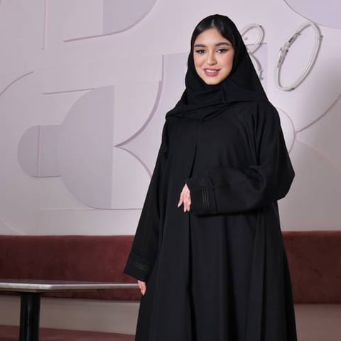 عباية سوداء مغلقة بطقطق بقصة كلوش واسعة وتطريز ذهبي ناعم على الأكمام و الطرف السفلي