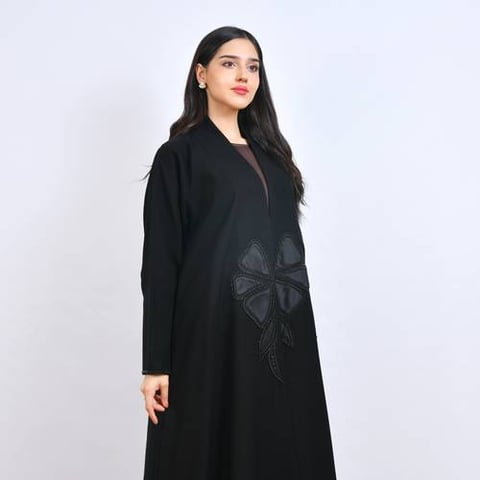 عباية سوداء فاخرة بتصميم عصري أنيق، تتميز بتطريز بارز على شكل زهرة مزينة بشك بقَصّة نص كلوش