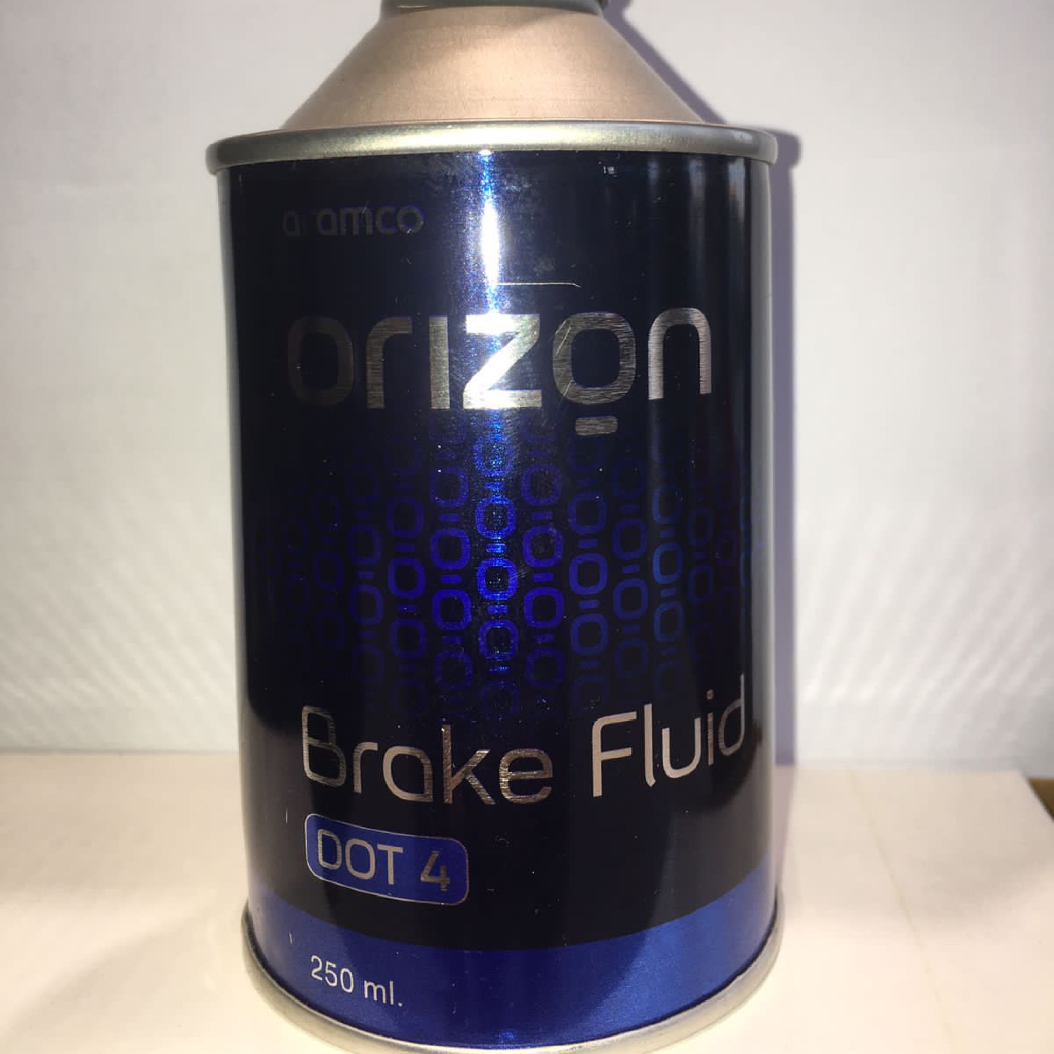A 250ml cylindrical black and blue metal can of Orizon Aramco Brake Fluid DOT 4