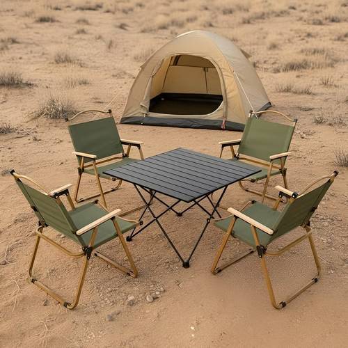 Multi-piece camping set | Black table with multi-size pointed legs and carrying bag, and several green chairs with gold frame and armrests.