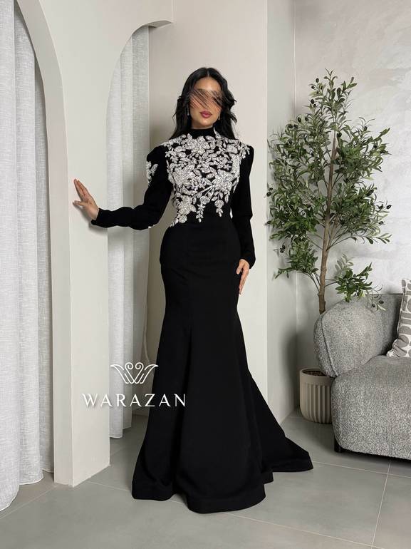 فستان سهرة أسود محتشم بياقة عالية وتطريز كريستال فضي على الصدر والأكتاف