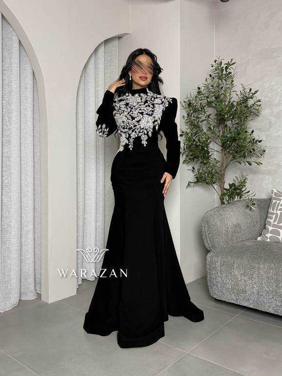 فستان سهرة أسود محتشم بياقة عالية وتطريز كريستال فضي على الصدر والأكتاف