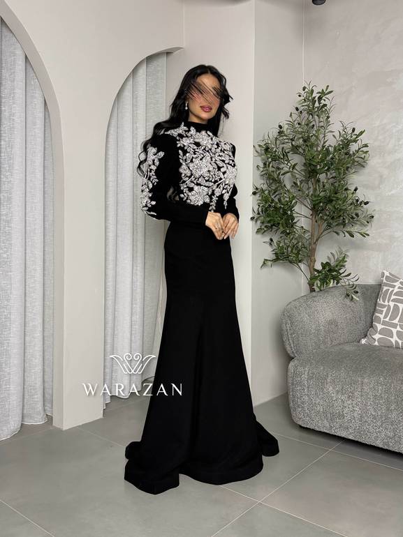 فستان سهرة أسود محتشم بياقة عالية وتطريز كريستال فضي على الصدر والأكتاف