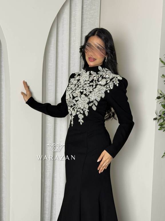 فستان سهرة أسود محتشم بياقة عالية وتطريز كريستال فضي على الصدر والأكتاف