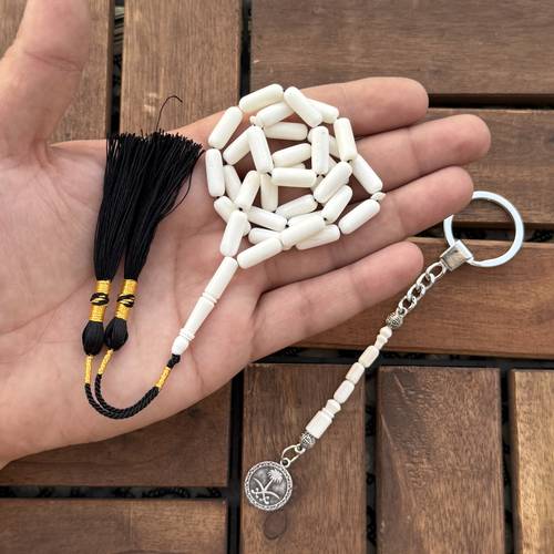 عظم جمل (خامة طبيعية) عدد الخرز 33 مقاس الخرز 6*15.5ملي بكركوشة قماش تفصيل + ميدالية للمفاتيح بعظم وشعار سيفين ونخلة 